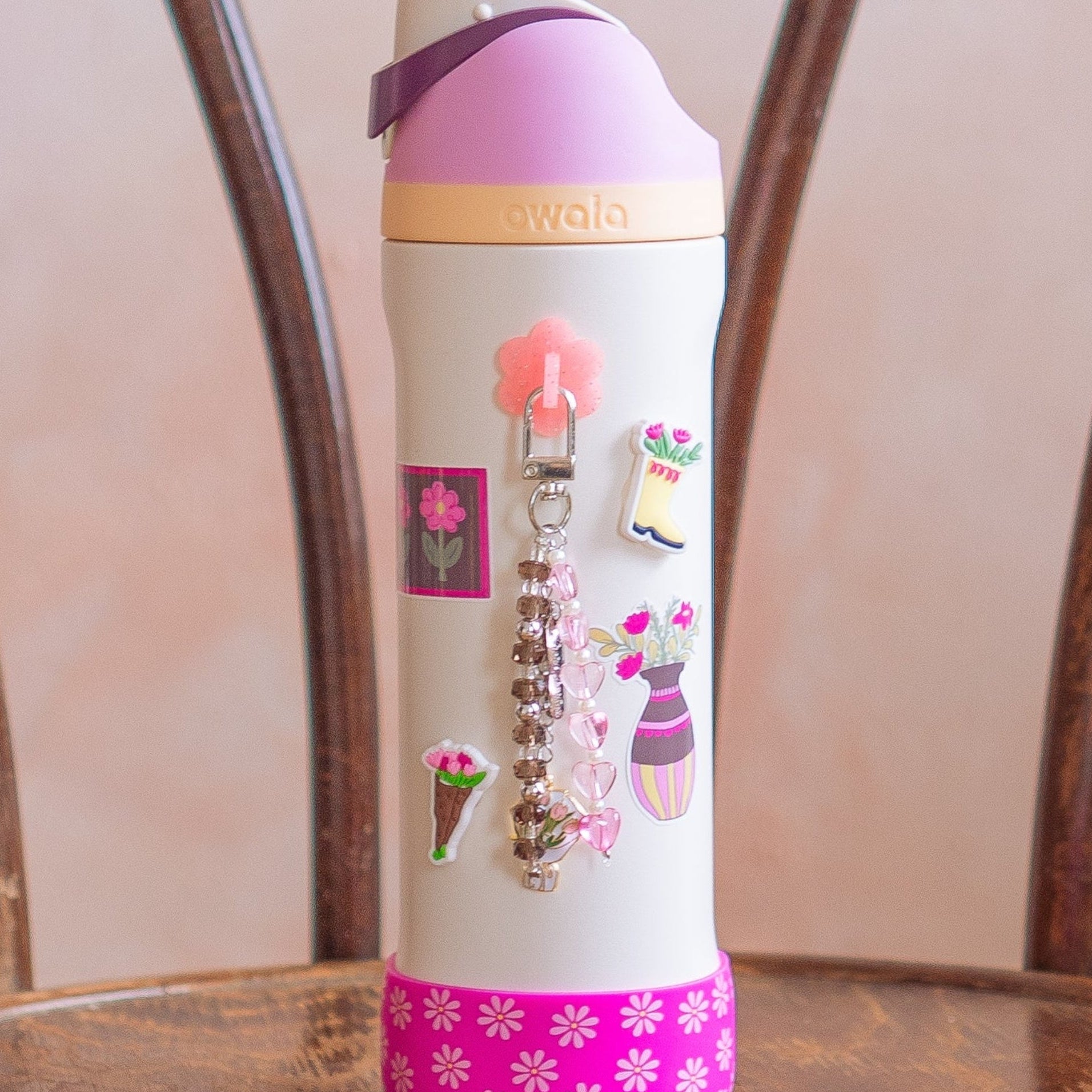 White water bottle with pink accents and decorative elements on a wooden chair.