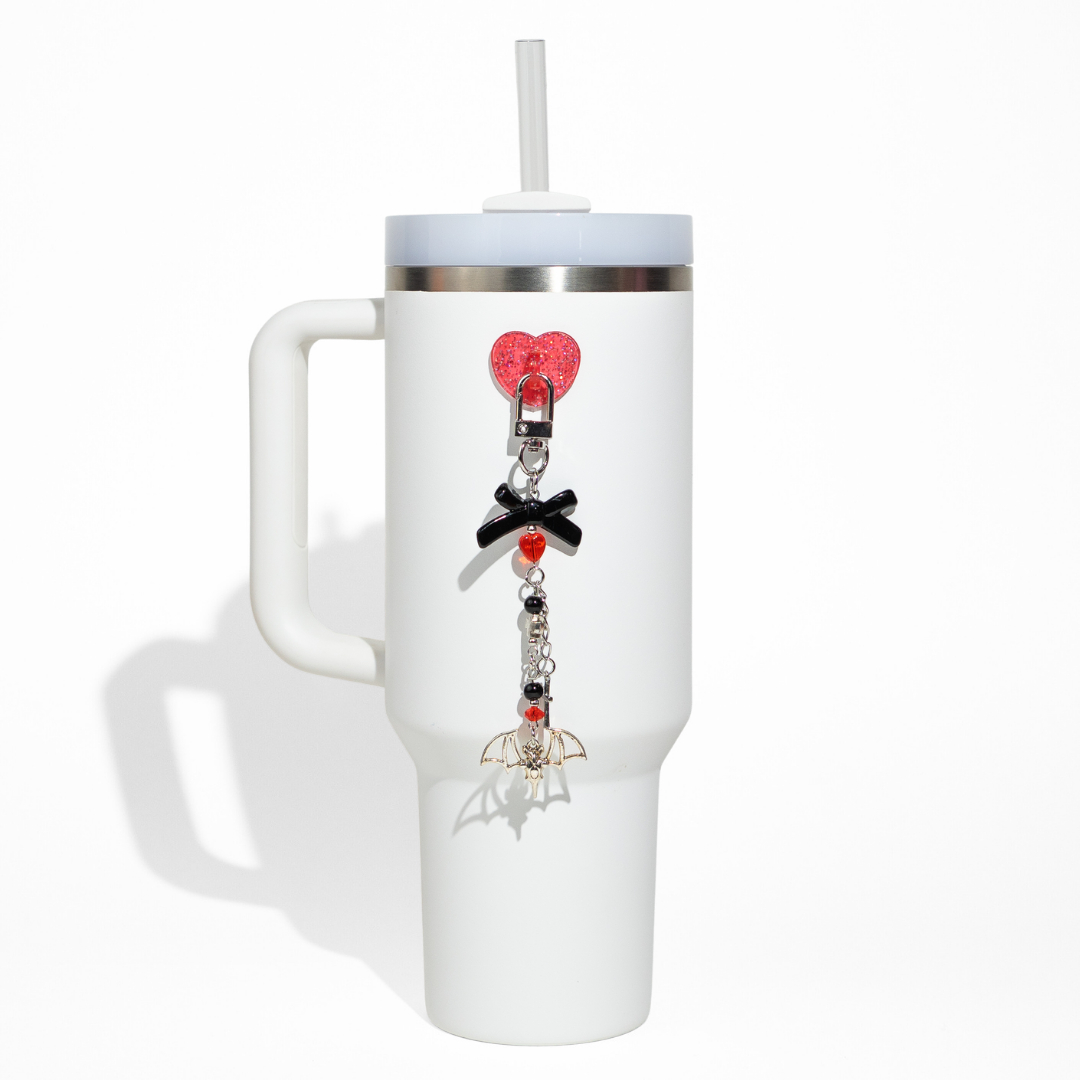 White tumbler with a gothic-style bottle charm featuring red heart clip, black bow, and silver bat pendant from CharCharms